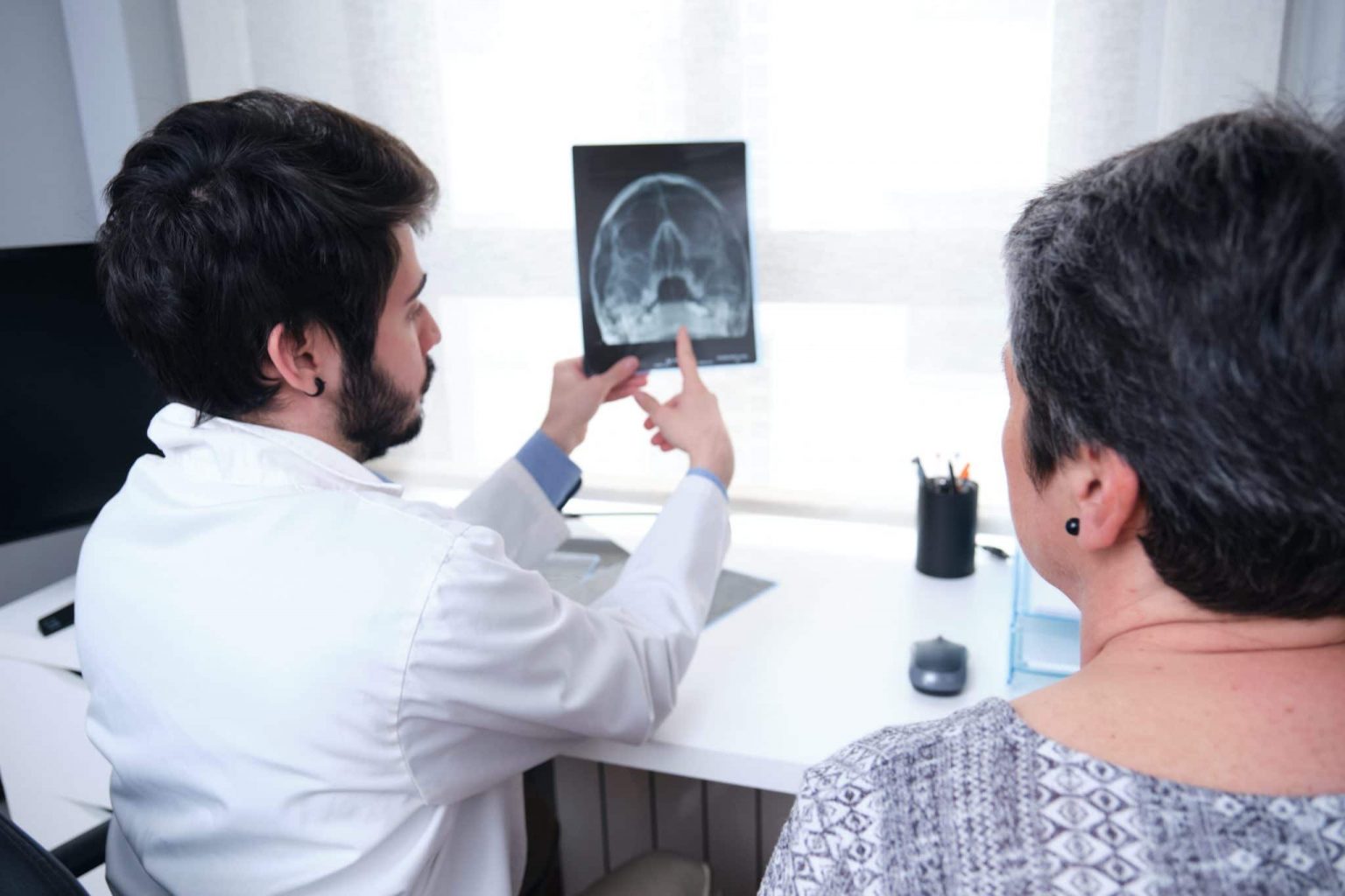 Doctor pointing to an x-ray of the sinuses while patient looks.